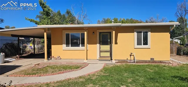 a view of a house with small yard plants and large tree