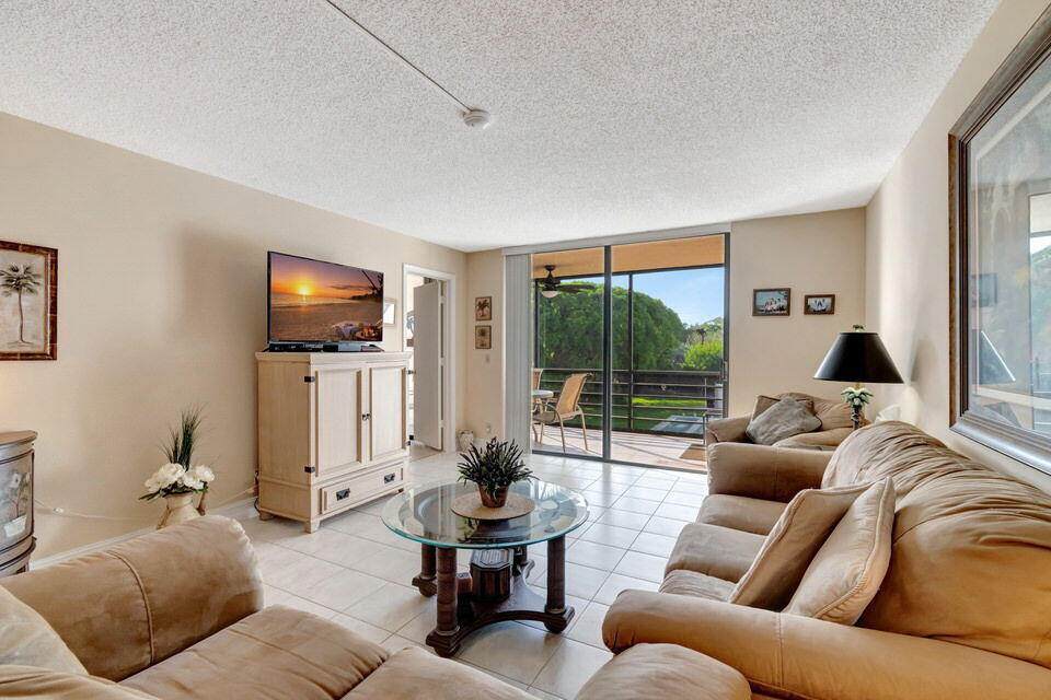555 Banyan Tree Lane, Unit 302 Delray Beach, FL 33483 - Photo 40 of 69 a living room with furniture a large window and a flat screen tv