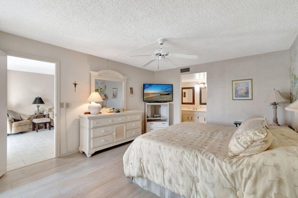 555 Banyan Tree Lane, Unit 302 Delray Beach, FL 33483 - Photo 50 of 69 a spacious bedroom with a bed a table and chair