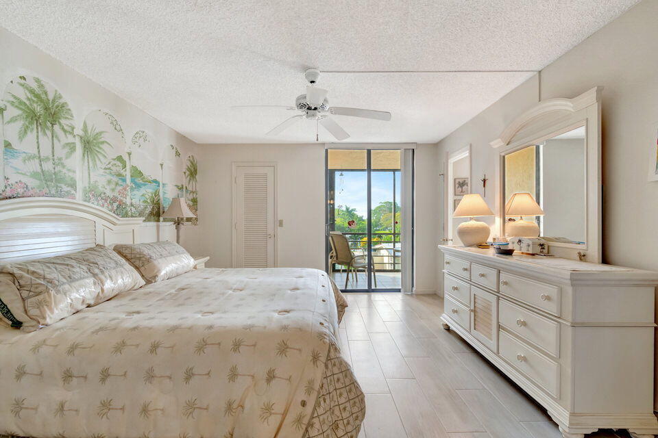 555 Banyan Tree Lane, Unit 302 Delray Beach, FL 33483 - Photo 51 of 69 a spacious bedroom with a large bed and a chandelier