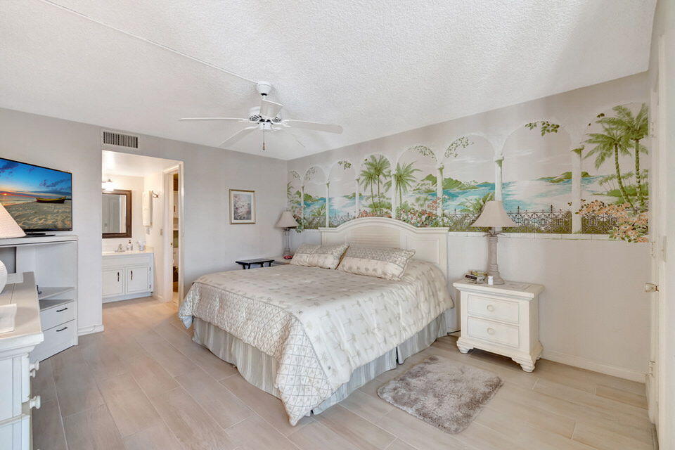 555 Banyan Tree Lane, Unit 302 Delray Beach, FL 33483 - Photo 54 of 69 a spacious bedroom with a bed and a flat screen tv