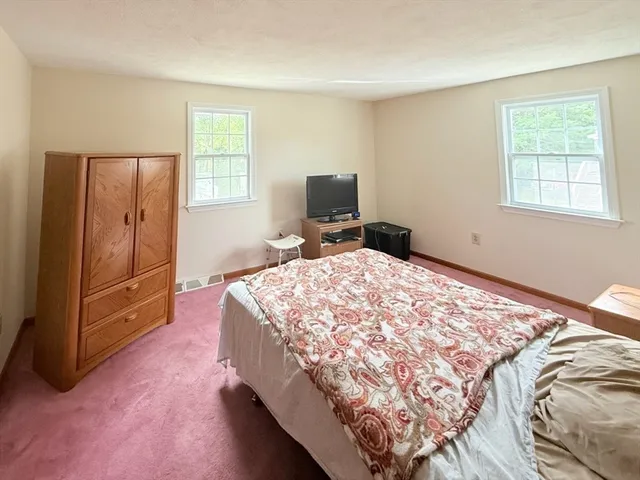 a bedroom with a bed and a flat tv screen on a dresser