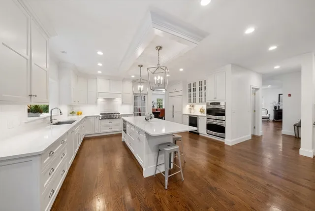 a kitchen with stainless steel appliances granite countertop a stove top oven a sink a dining table and chairs with wooden floor