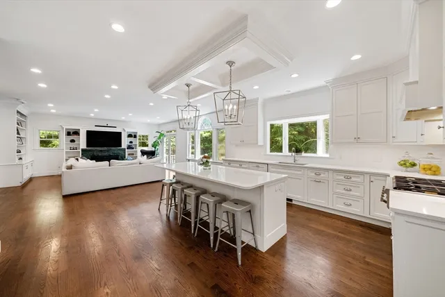 a large kitchen with kitchen island a stove a sink a refrigerator and a dining table with wooden floor