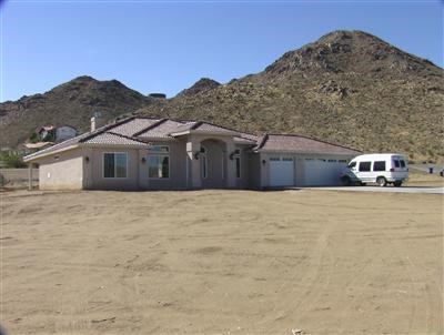16182 Serrano Road Apple Valley, CA 92307 - Photo 1 of 1 a front view of a house with a yard and mountain view in back