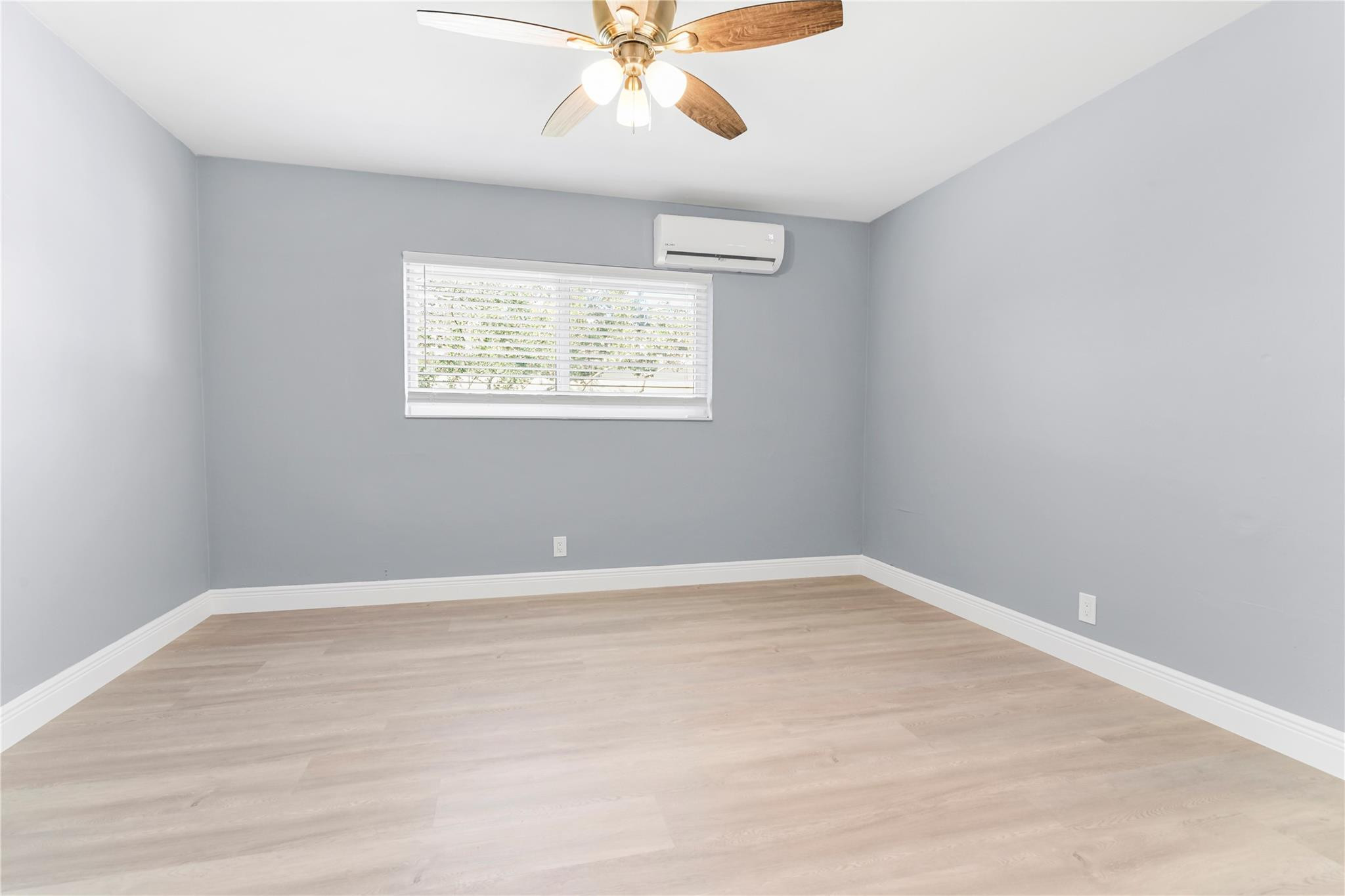 4751 Northeast 21st Terrace, Unit 3 Lighthouse Point, FL 33064 - Photo 13 of 18 an empty room with wooden floor chandelier fan and windows
