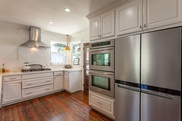 a kitchen with stainless steel appliances granite countertop a refrigerator a stove and white cabinets with wooden floors