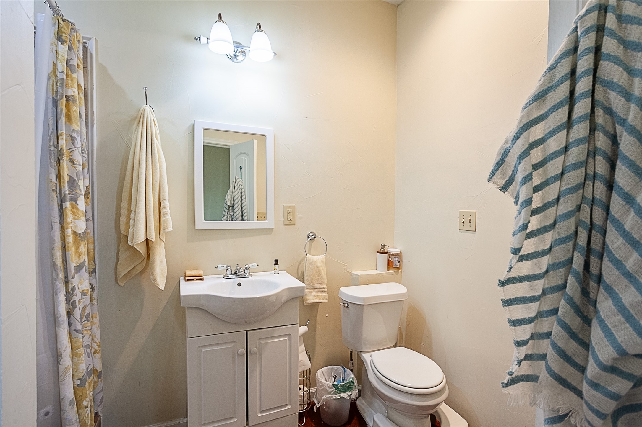 260 Manor Street Beaumont, TX 77706 - Photo 45 of 50 a bathroom with a sink a toilet a mirror and shower curtain