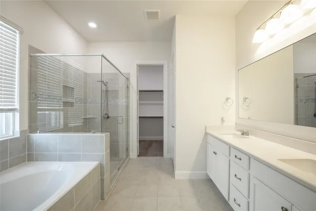 a spacious bathroom with a tub sink and mirror