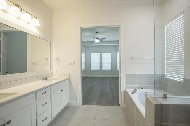 a spacious bathroom with a tub sink and mirror