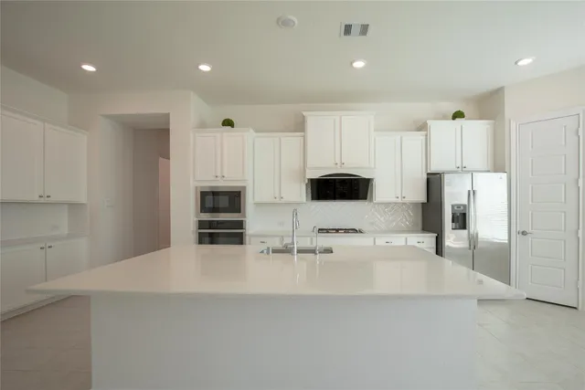 a kitchen with stainless steel appliances kitchen island granite countertop a refrigerator and a stove top oven