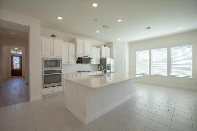 a kitchen with kitchen island granite countertop a sink and stainless steel appliances
