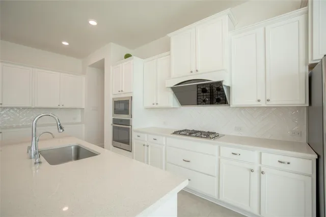 a kitchen with granite countertop white cabinets and stainless steel appliances