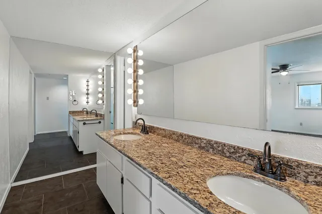 a bathroom with a granite countertop sink and a mirror