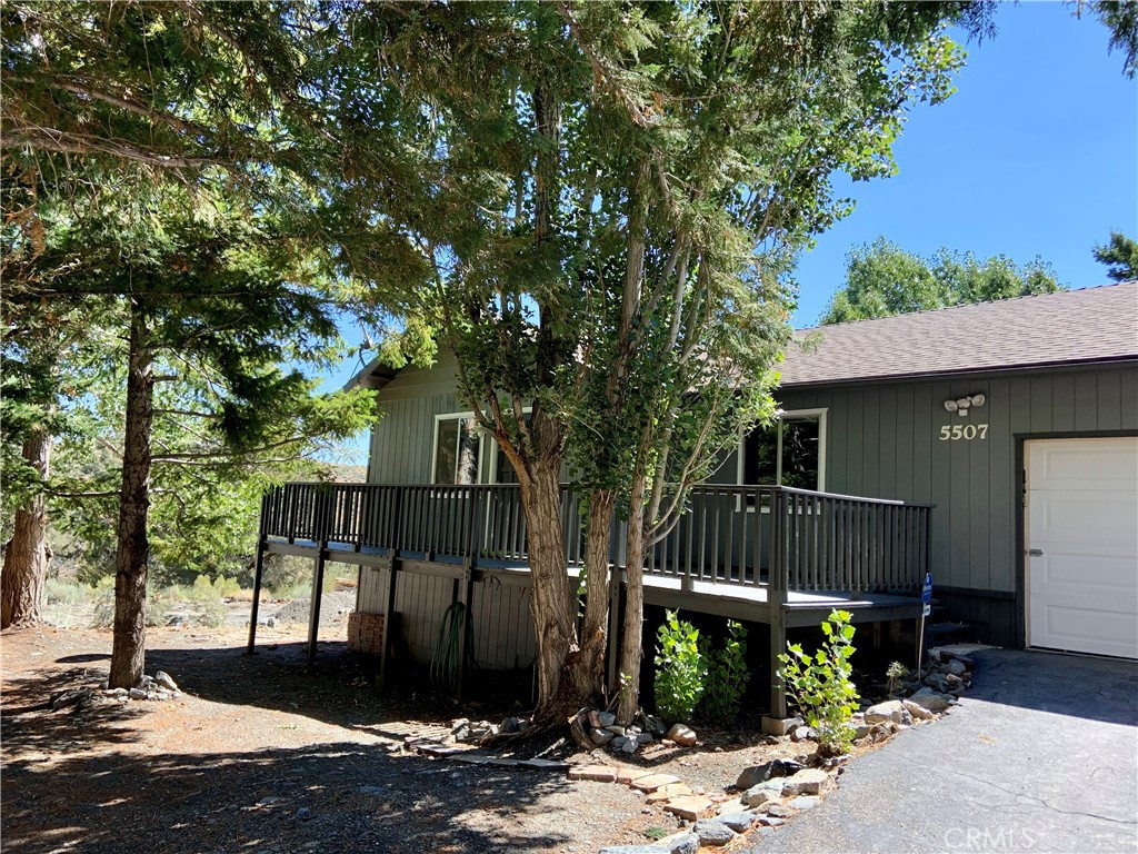 a view of a house with large tree and wooden fence