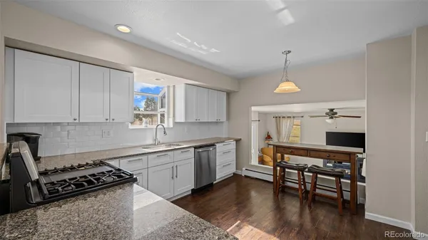 a kitchen with stainless steel appliances a stove a sink cabinets and wooden floor