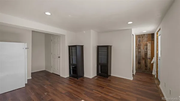 a view of an empty room with wooden floor and closet