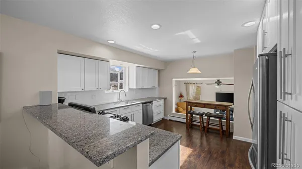 a kitchen with stainless steel appliances granite countertop a sink dishwasher a stove and a refrigerator with wooden floor