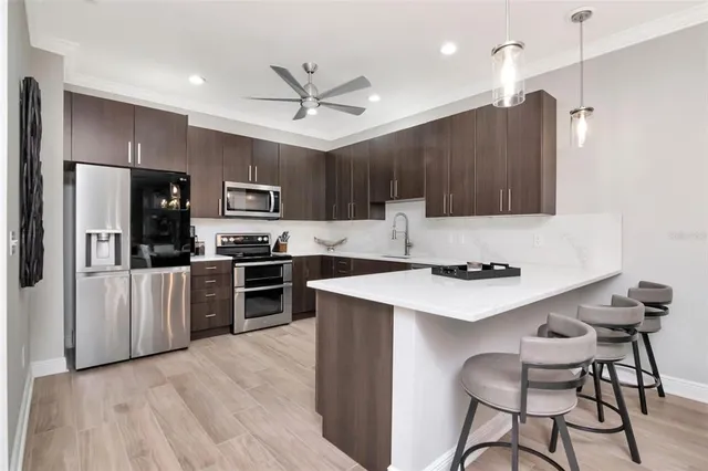 a kitchen with granite countertop a refrigerator stove a sink and chairs