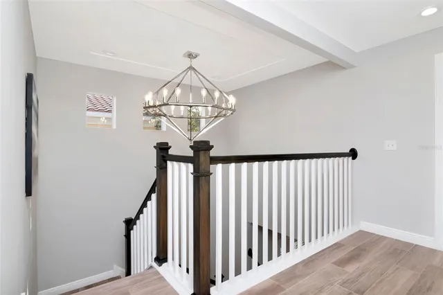 a view of a hallway with a chandelier wooden floor and chandelier