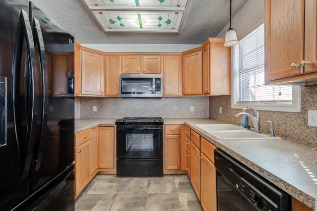 a kitchen with stainless steel appliances granite countertop a sink stove microwave and refrigerator