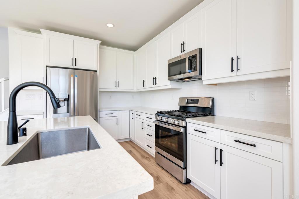 30343 Singer Lane Menifee, CA 92584 - Photo 2 of 24 a kitchen with stainless steel appliances granite countertop a white stove top oven a sink and dishwasher