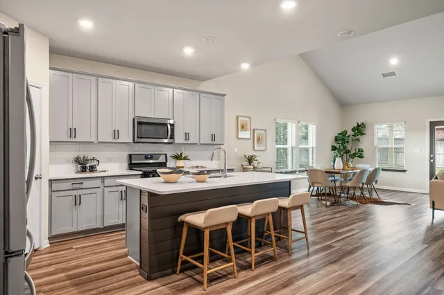 a kitchen with stainless steel appliances granite countertop a table chairs sink and cabinets