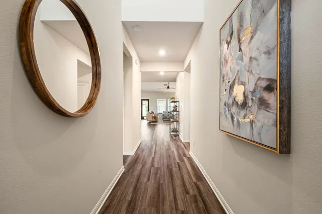 a view of a hallway with wooden floor and a bathroom