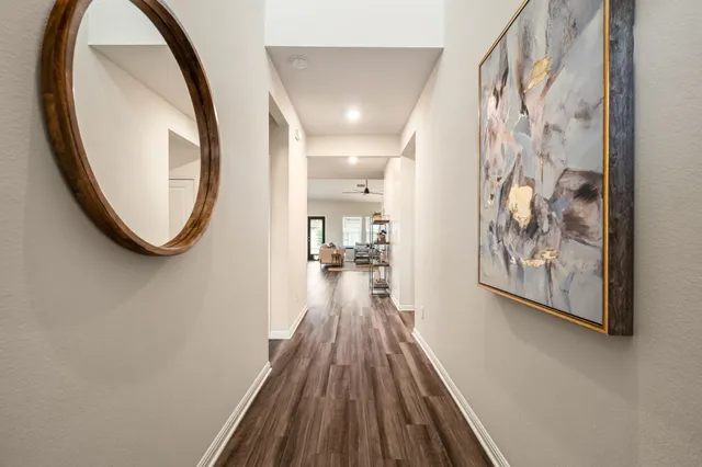 a view of a hallway with wooden floor and a bathroom