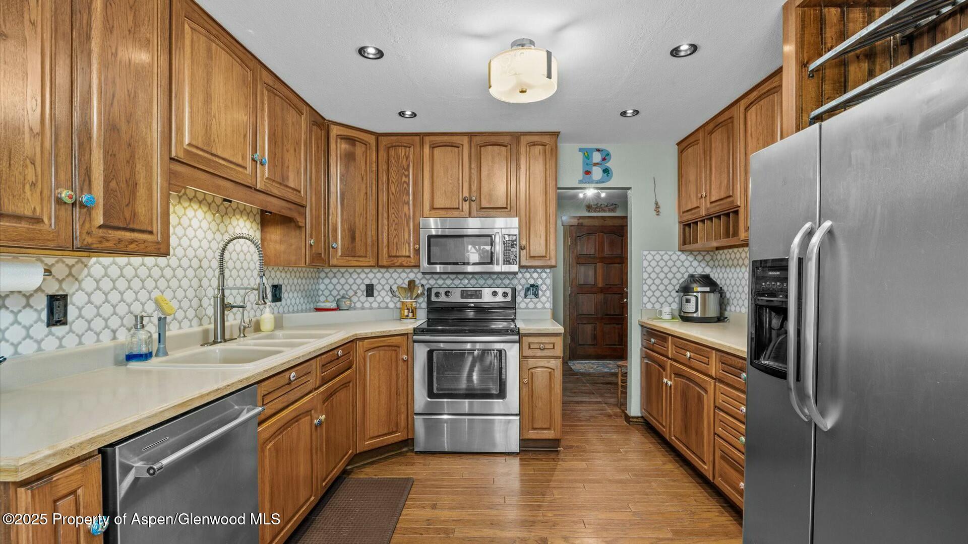1201 Fir Avenue Rifle, CO 81650 - Photo 11 of 25 a kitchen with stainless steel appliances granite countertop a refrigerator a stove and a sink with wooden floor