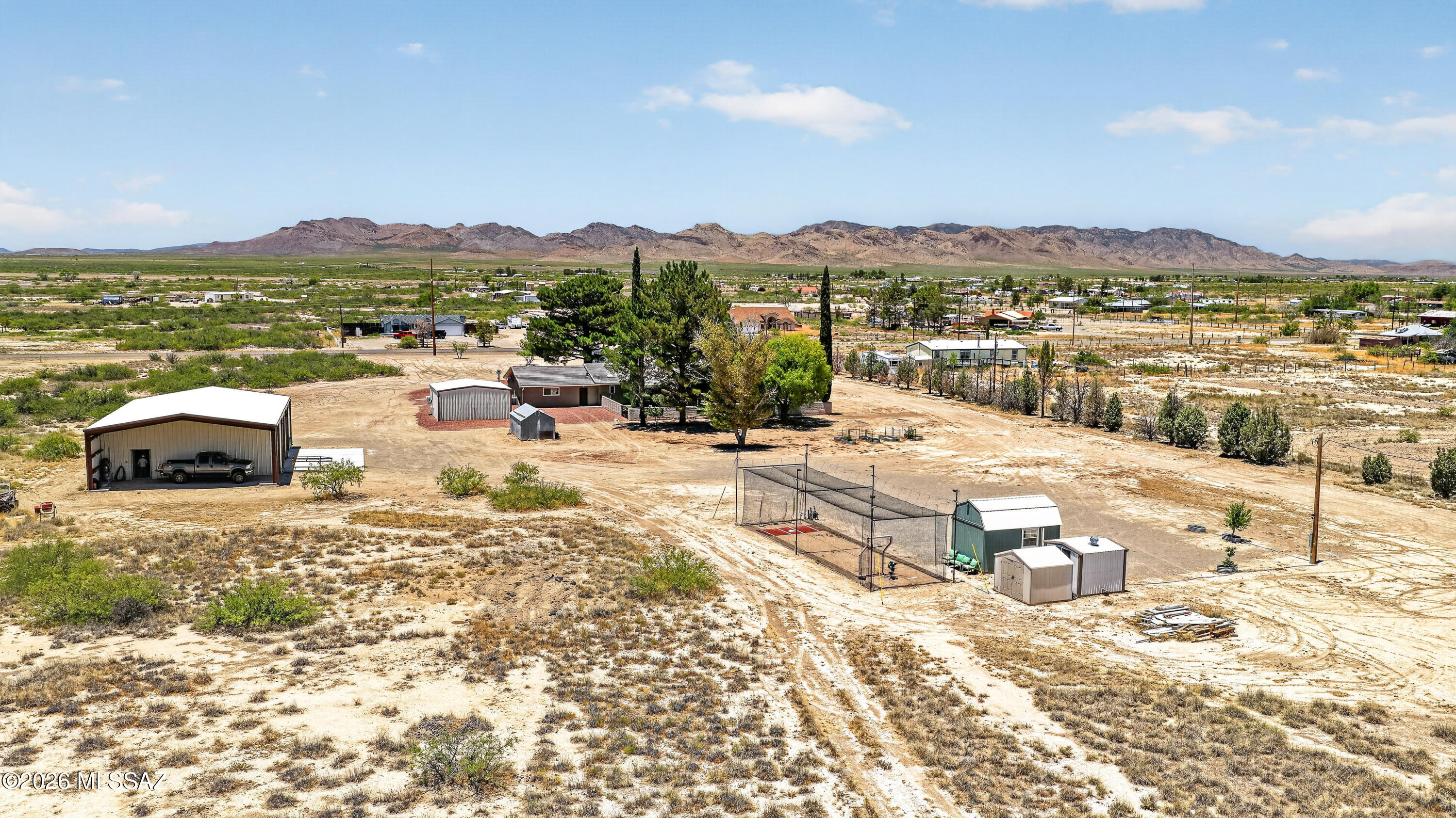 194 Taylor Road Willcox, AZ 85643 - Photo 48 of 54 Aerial views capture the full property layout, including the west-facing home, detached shop and outbuildings, circular driveway, mature trees, and beautiful mountain views.