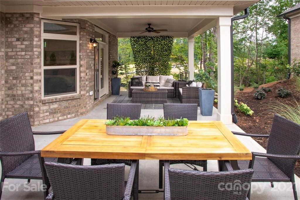 2023 New Style Way, Unit 24 Tega Cay, SC 29708 - Photo 17 of 18 a view of a patio with table and chairs potted plants and floor to ceiling window