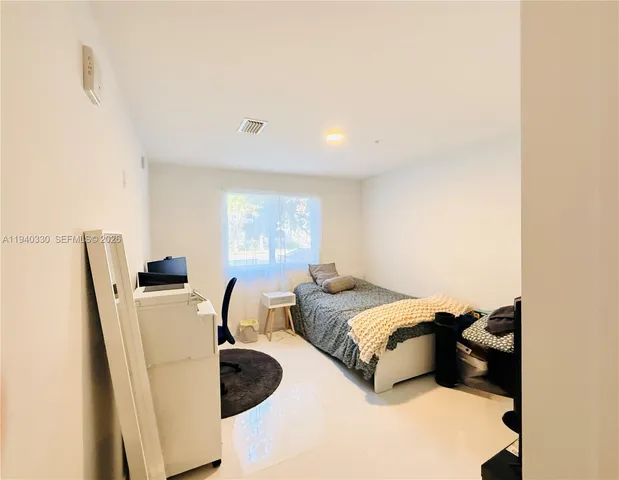 a bedroom with a bed and a refrigerator