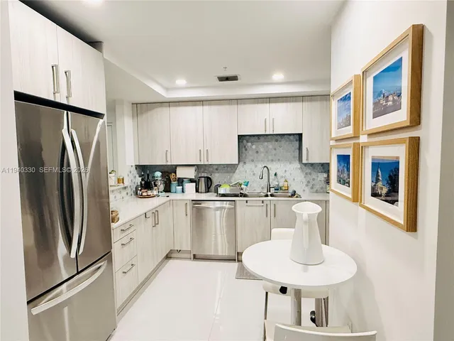 a kitchen with stainless steel appliances granite countertop a refrigerator a sink a stove a dining table and chairs