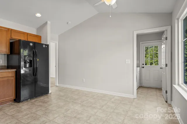 a view of a refrigerator in kitchen and an empty room