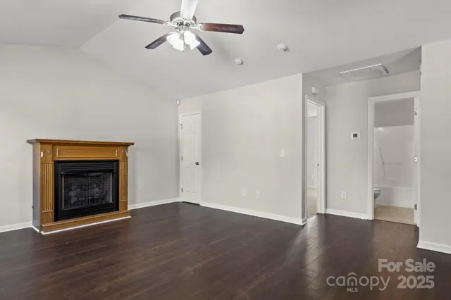 a view of an empty room with wooden floor and a fireplace