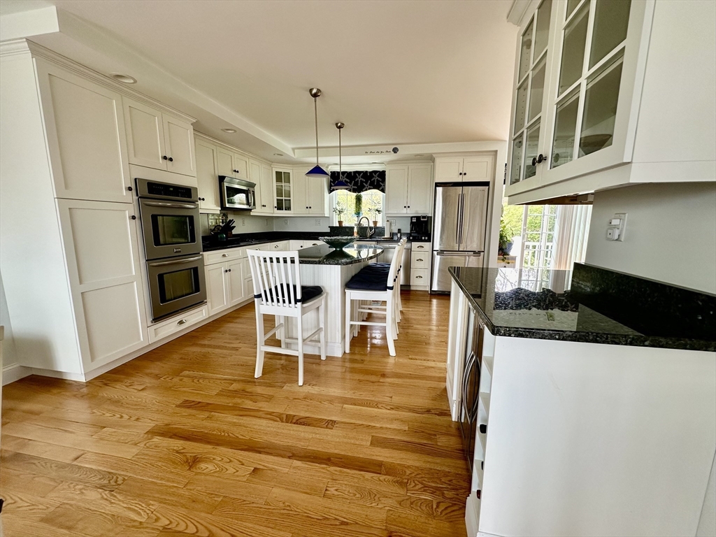1467 State Road Plymouth, MA 02360 - Photo 5 of 31 a kitchen with stainless steel appliances granite countertop a stove top oven a sink a dining table and chairs with wooden floor