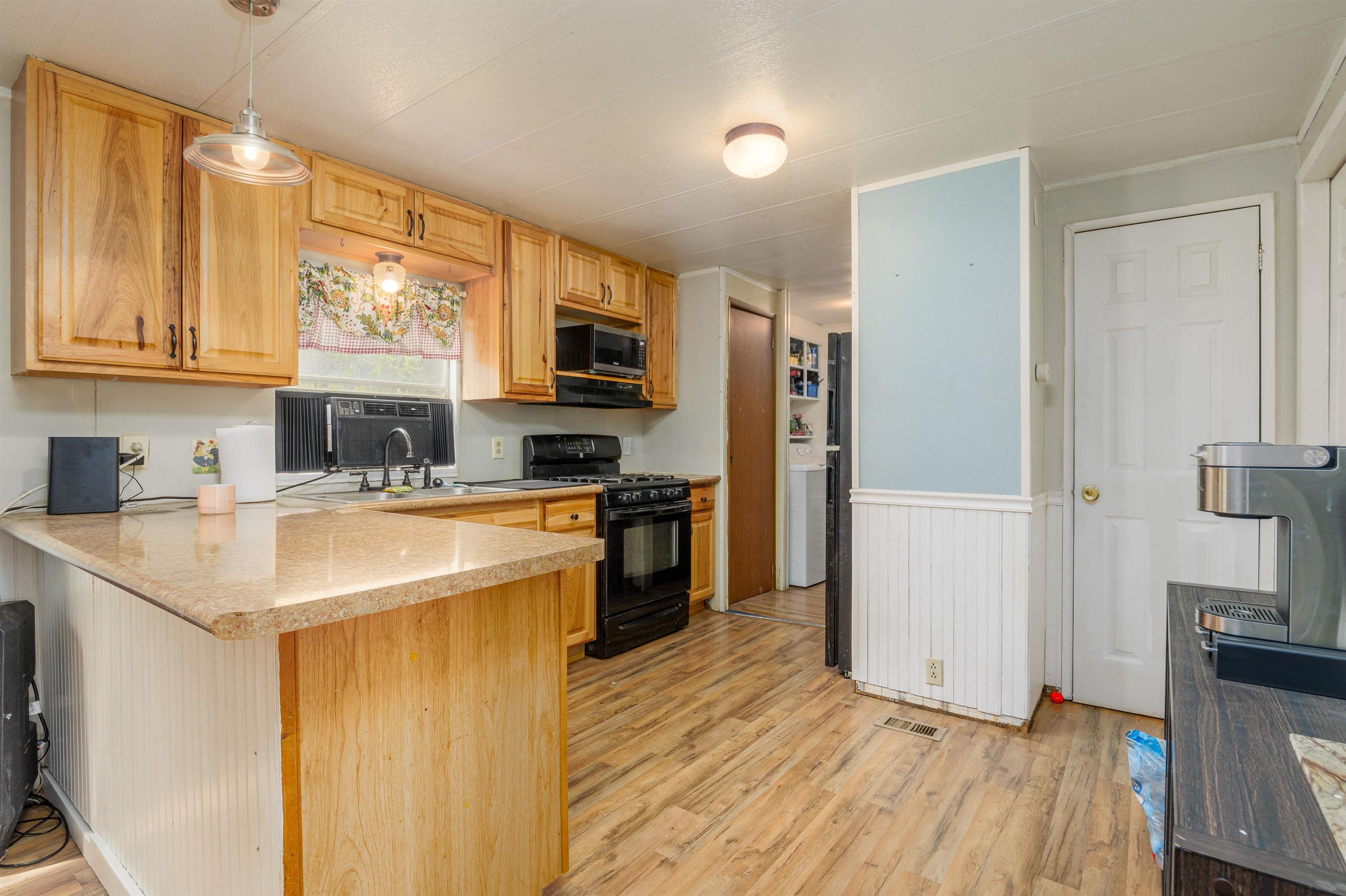 265 Southwest 11th Avenue Cedaredge, CO 81413 - Photo 10 of 39 a kitchen with stainless steel appliances a refrigerator a stove a sink and white cabinets with wooden floor