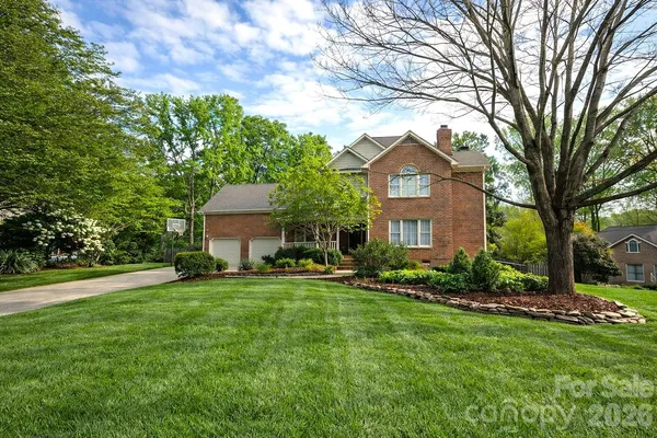 a front view of a house with a garden and trees