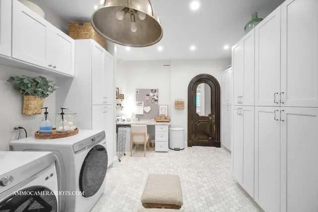 a spacious bedroom with a bed a chandelier and dresser