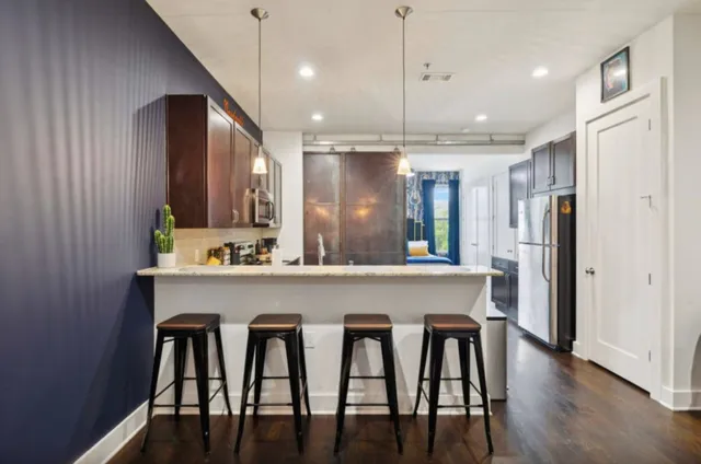 a kitchen with stainless steel appliances a dining table chairs refrigerator and cabinets