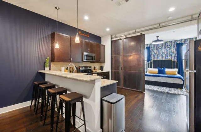 a kitchen with stainless steel appliances kitchen island granite countertop a refrigerator a stove and a dining table with wooden floor