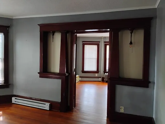 a view of empty room with wooden floor and fan