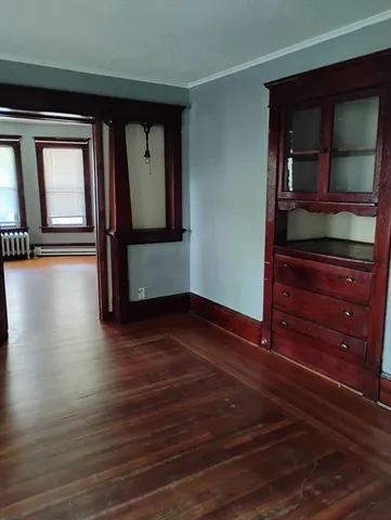 a view of a hallway with wooden floor and cabinet