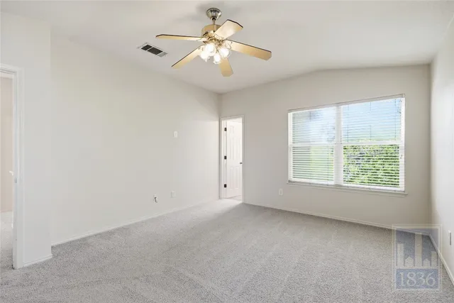 an empty room with a chandelier fan and windows