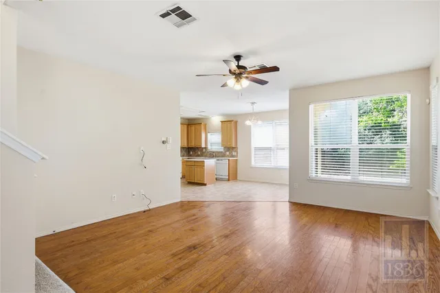 a view of a big room with wooden floor and windows