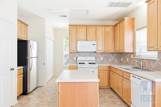 a kitchen with a sink a counter top space stainless steel appliances cabinets and a large window
