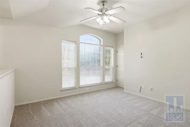 an empty room with windows and ceiling fan