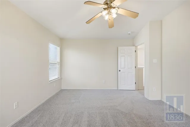 an empty room with windows and chandelier fan