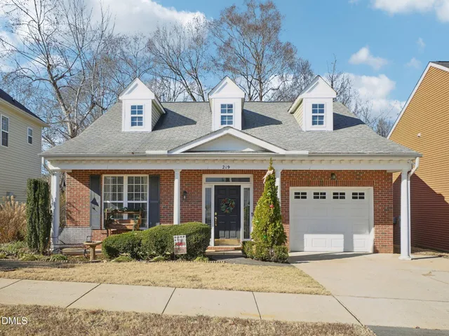 a view of a white house with large windows and a table and chairs in front of it